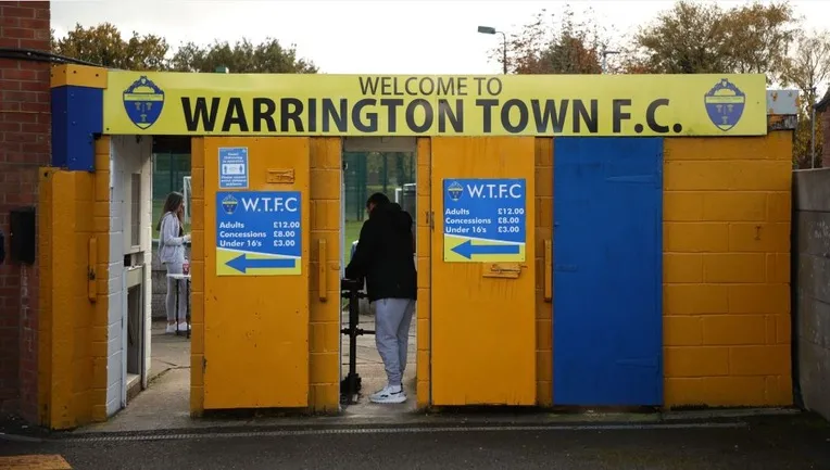 Cổng vào sân Cantilever Park với hàng rào và lối đi dành cho khán giả đến xem các trận đấu của Warrington Town FC.