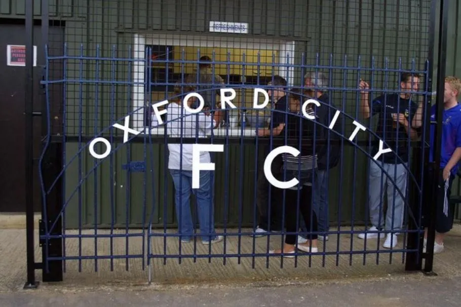 Hàng rào và khung cảnh khán đài sân vận động Oxford City FC, thể hiện nét đặc trưng của bóng đá hạng dưới Anh.
