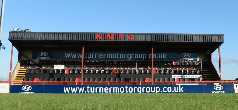 Khu vực khán đài chính tại sân Bloomfields, nơi cung cấp chỗ ngồi có mái che cho người hâm mộ Needham Market FC.