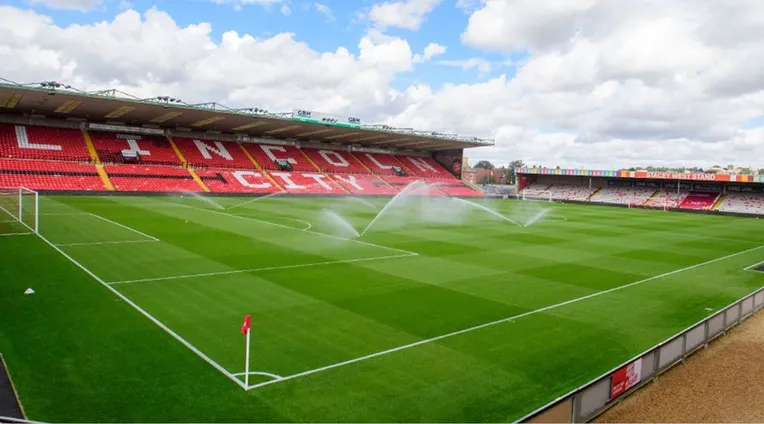 Khung cảnh sân đấu Sincil Bank với mặt cỏ xanh mướt, chuẩn mực bóng đá Anh
