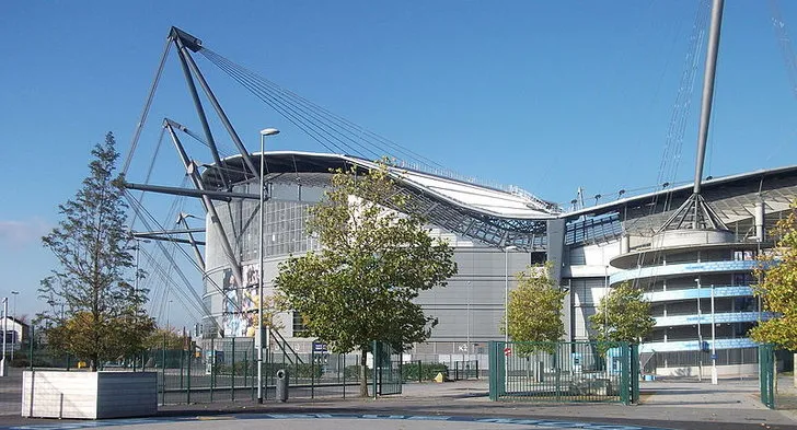 Mặt ngoài sân vận động Etihad với kiến trúc hiện đại và logo Manchester City